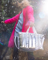 A silver duffle bag with iridescent confetti straps and a white detachable shoulder strap.