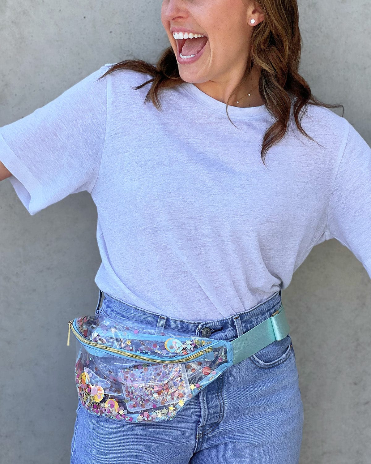 Girl wearing fanny pack around waist for easy carrying. Light blue clear confetti fanny pack.
