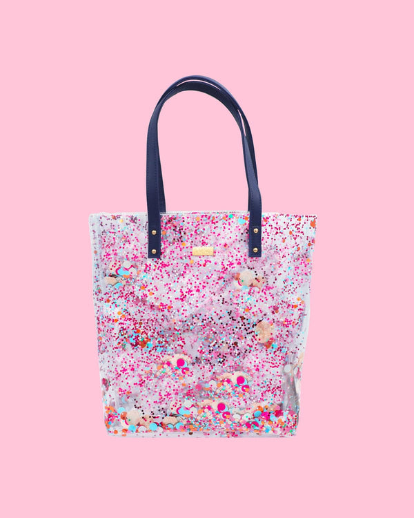 A clear, colorful confetti tote bag with navy straps. 