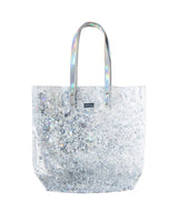 A clear, silver confetti tote bag with iridescent straps.