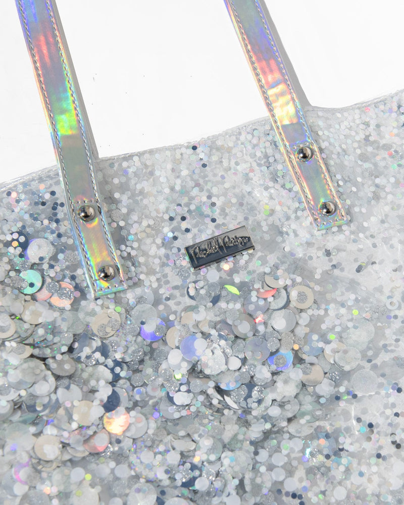A clear, silver confetti tote bag with iridescent straps.