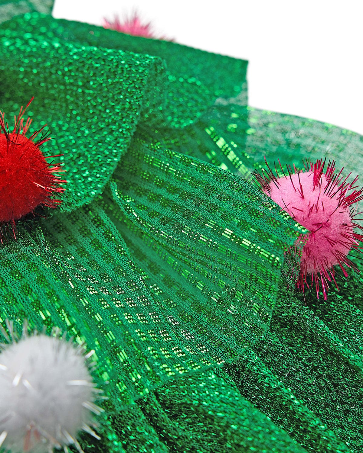 Close up of green multi-layer tulle and  tinsel pom details of Christmas tree hat shot against white background.