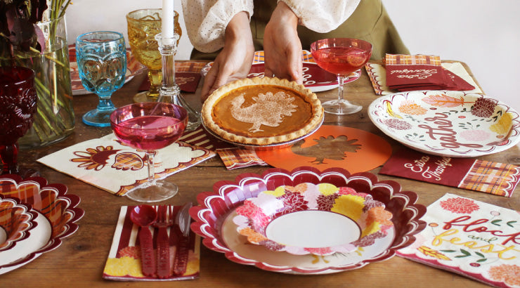 A thanksgiving table set with festive pattered paper plates and napkins. 
