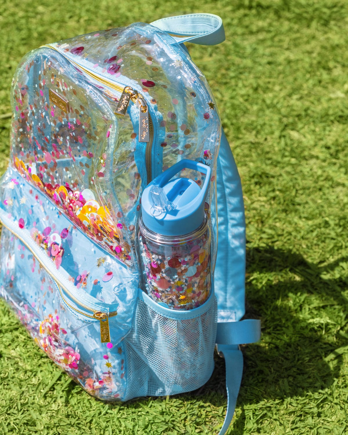Water bottle with straw in nylon mesh backpack pocket on grassy background