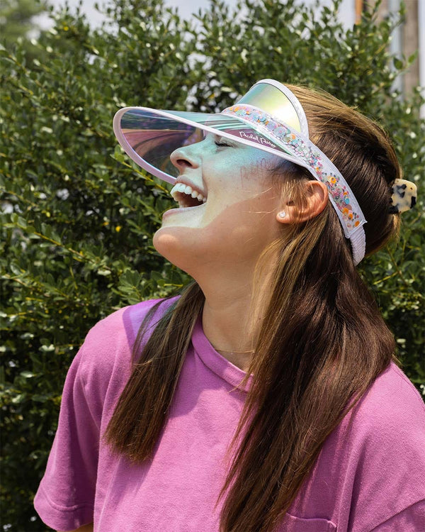 girl smiling in the summer sun with colorful visor with flower shop confetti