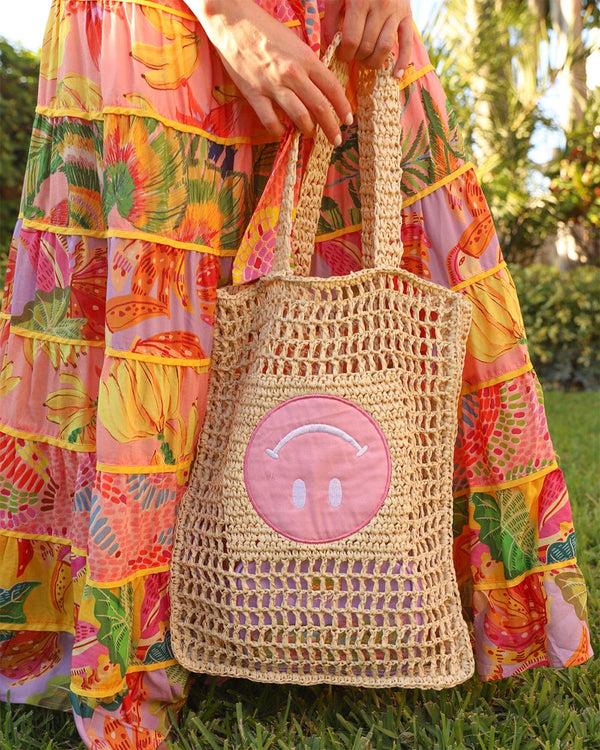 girl holding woven tote bag with tropical dress and floral sunglasses