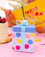 Colorful polka dots, light blue ribbon and gold straw on birthday present shaped novelty fun sipper cup.