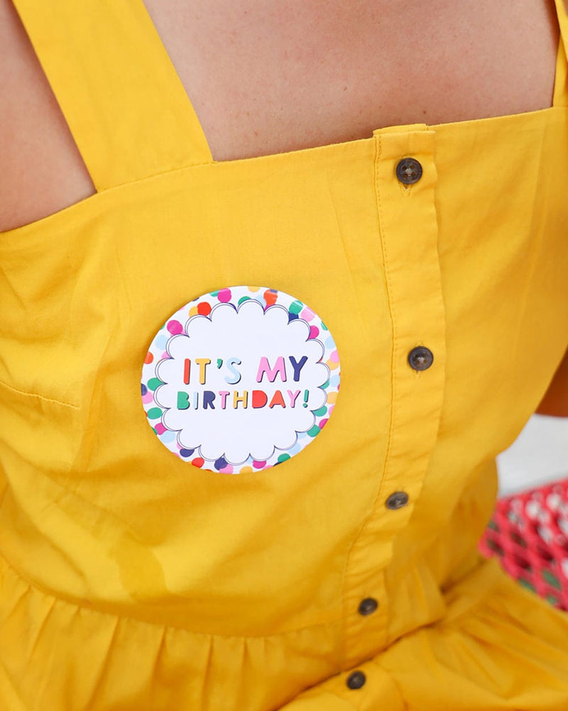 Girl wearing yellow dress, with birthday button pinned to her dress