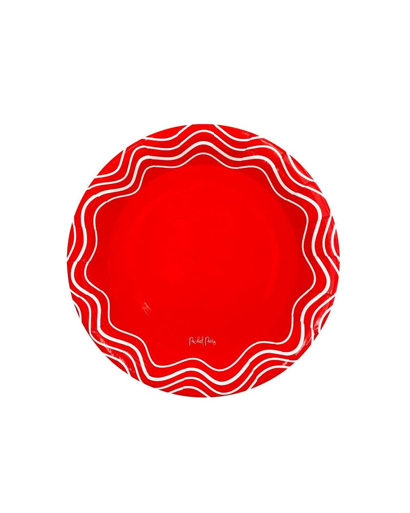 A red circular plate that has white waves along the rim. 