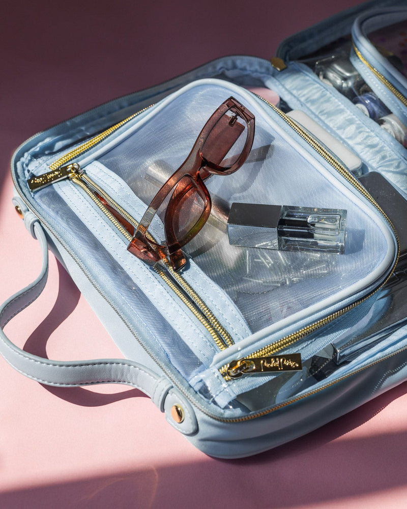 Sunglasses and lip gloss on open traveler makeup cosmetic case.