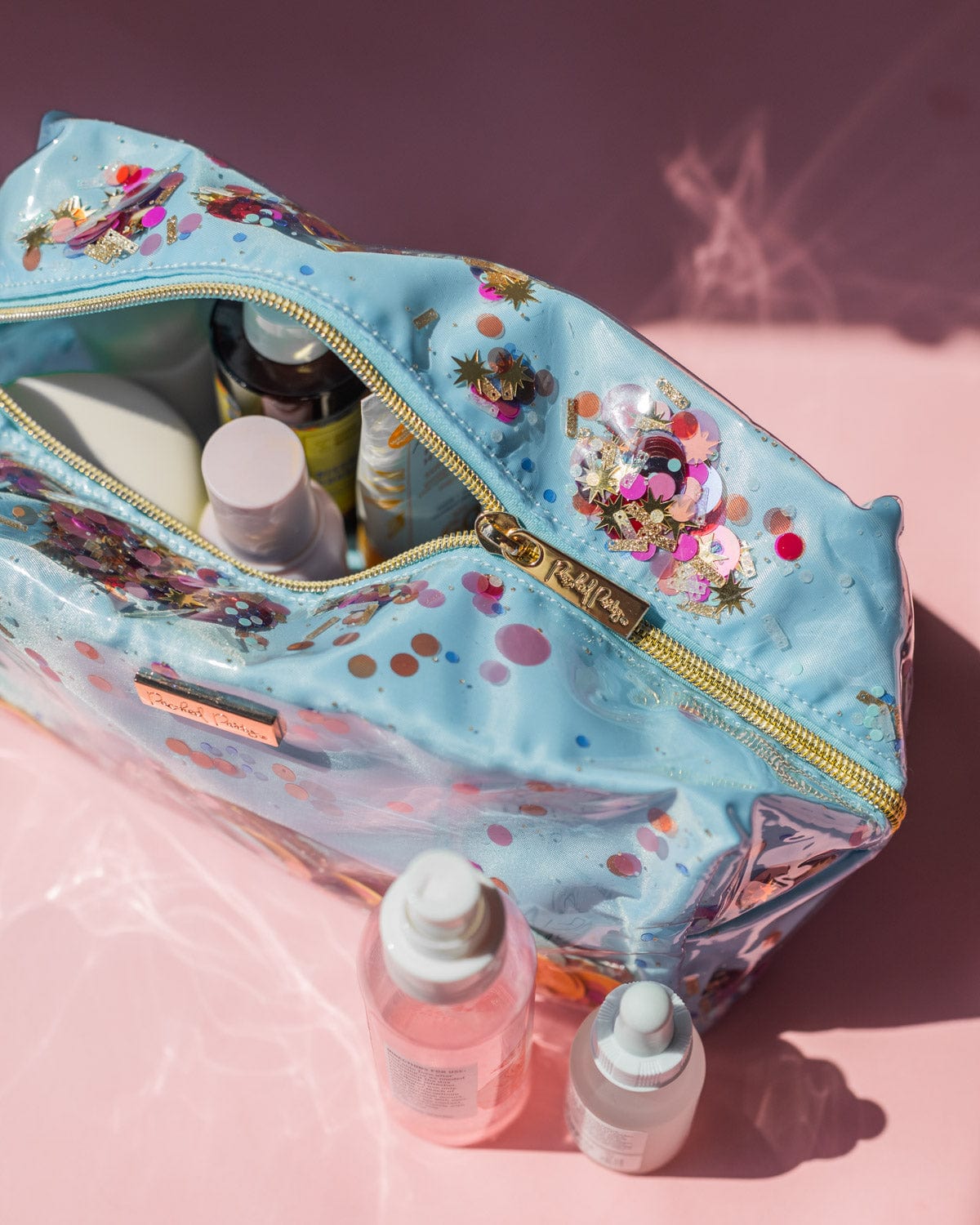 Gold zipper luxe material on makeup traveling bag full of beauty cosmetic products