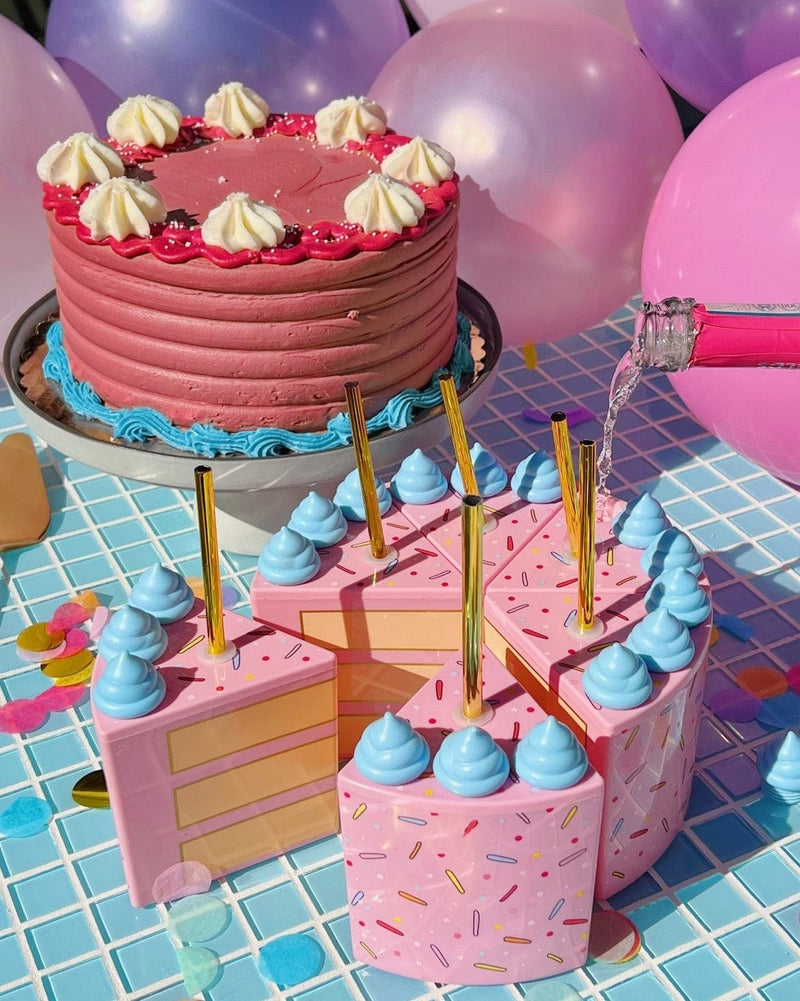 A set of 6 cake slice sippers with gold straws. Wine being poured in next to birthday cake and balloons in a party scene