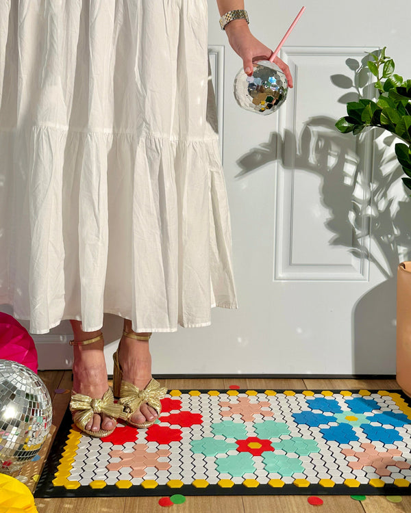 Girl holding disco ball sipper cup, standing on floral hexagon tile door mat. Perfect for a cute doorstep or porch.
