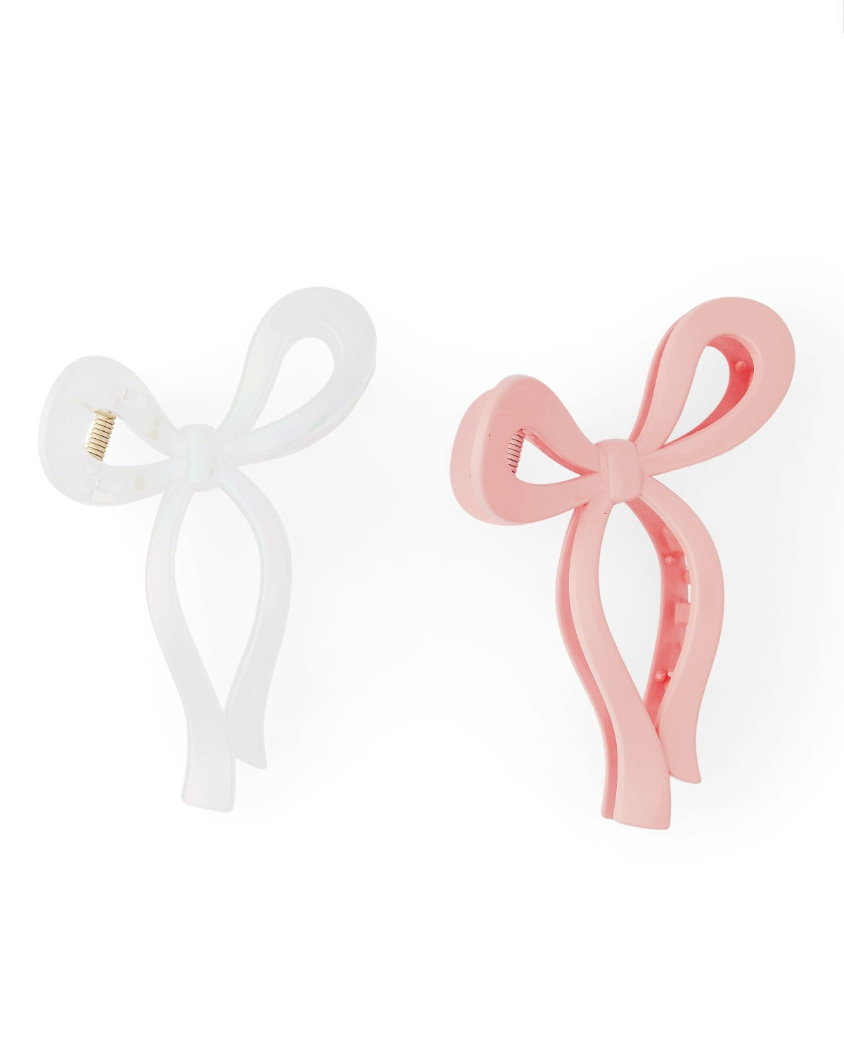 Two bow shaped claw clips sit against a white background. The bow on the left is white while the other is pink.
