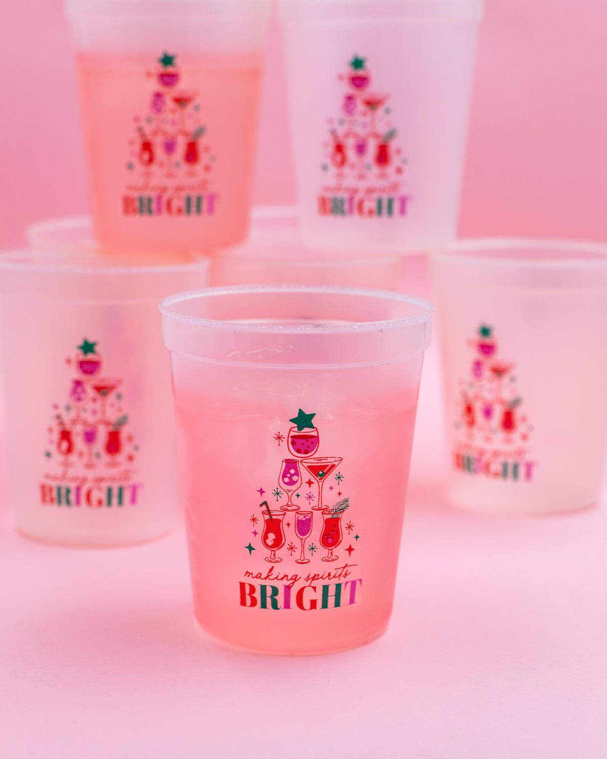'Making Spirits Bright' color changing cup with pink appearance shot against more cups and a pink background