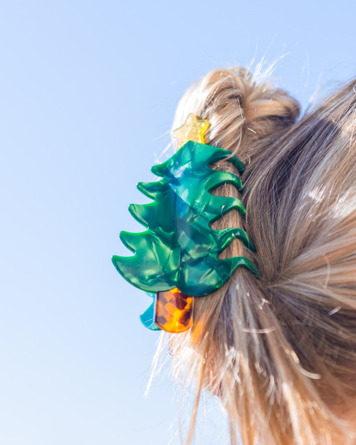 Christmas tree claw clip holding hair shot against sky background. 