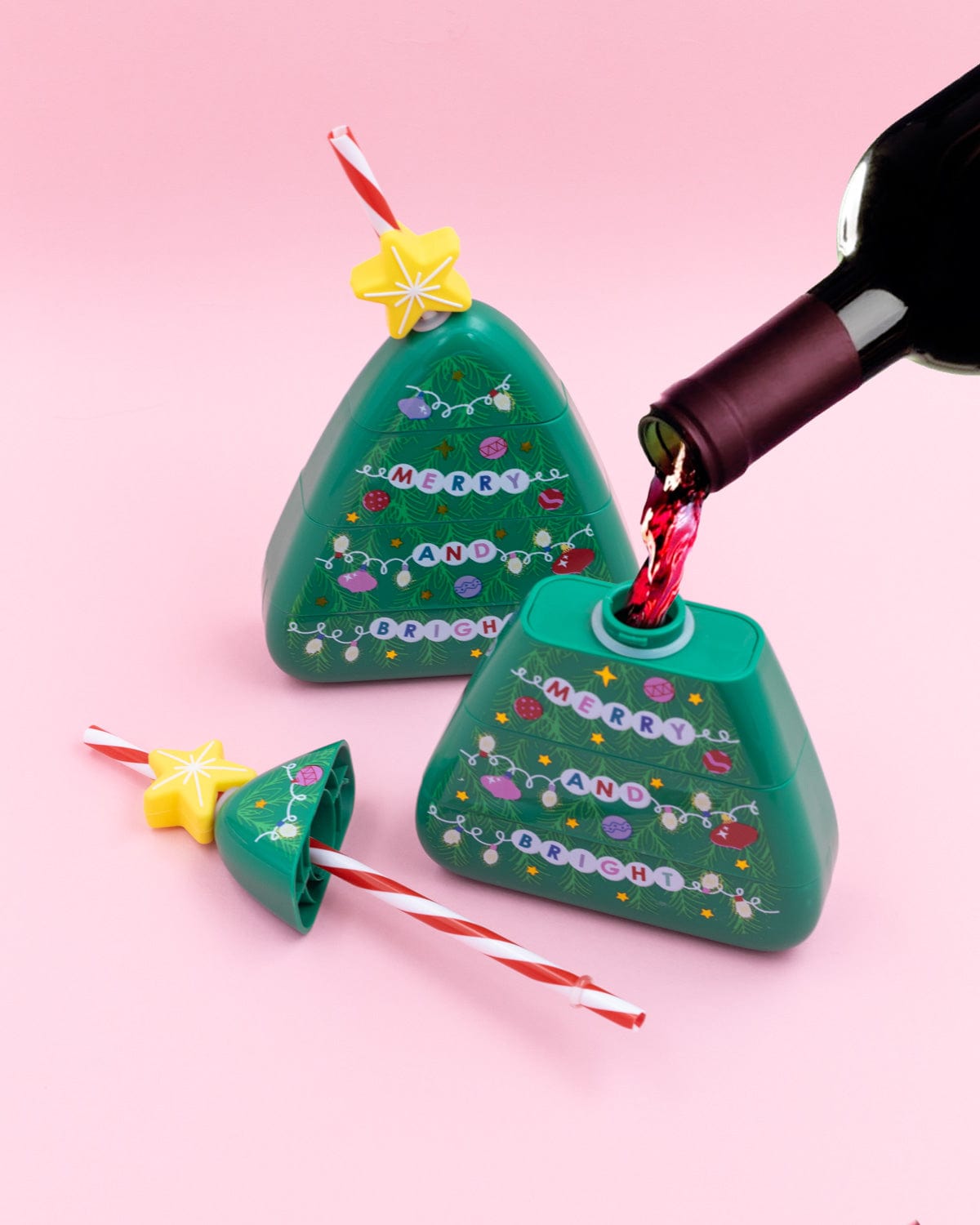 Wine being poured into Christmas Tree Sipper shot against pink background. 