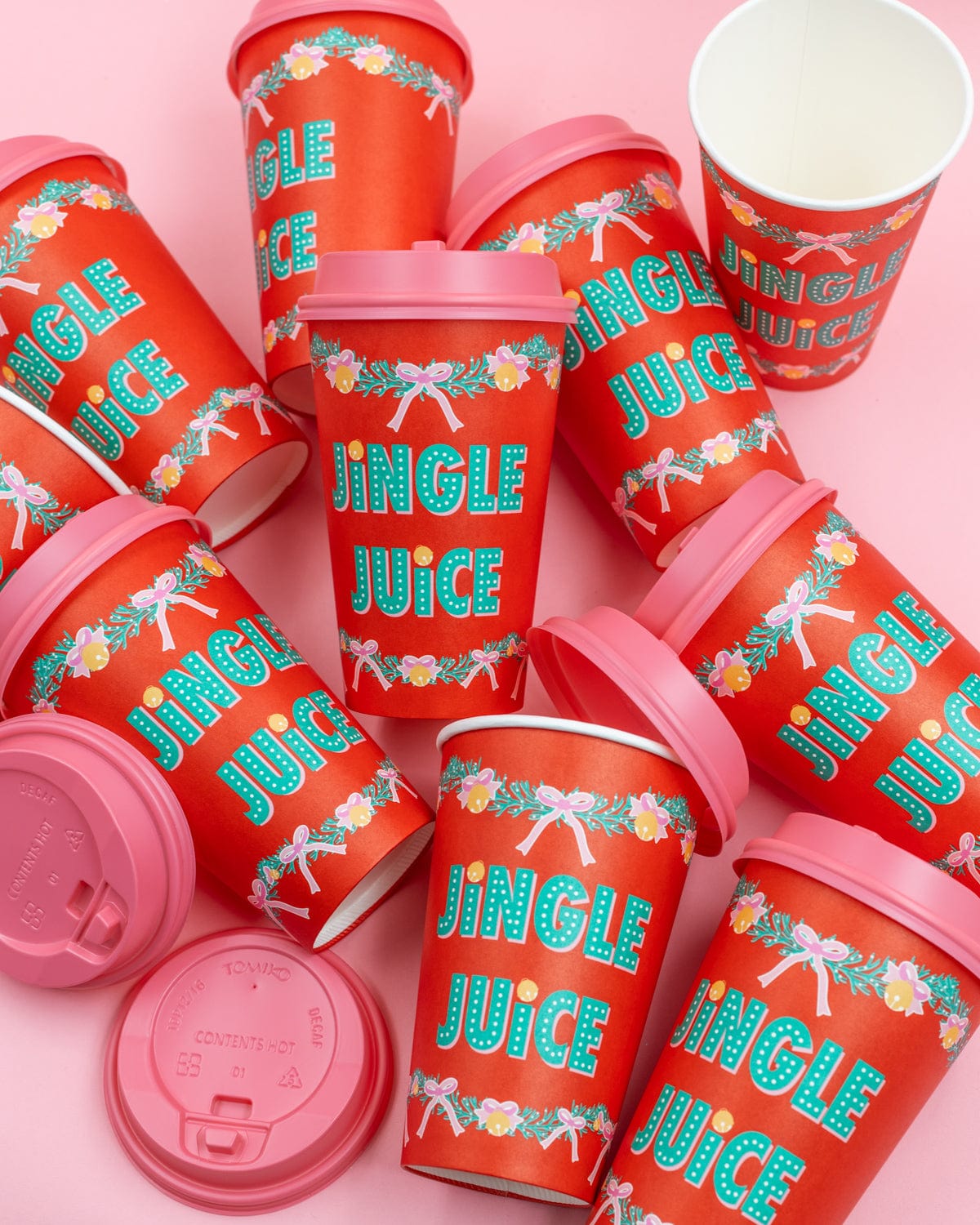 10 red to-go 'Jingle Juice' cups with pink lids shot against pink background. 