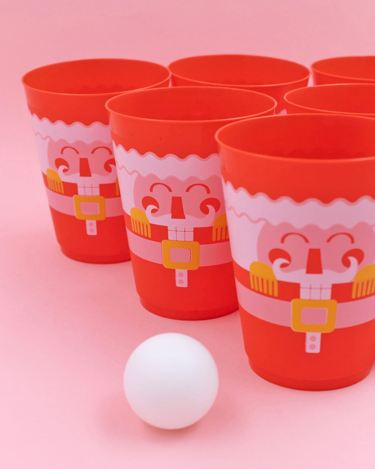 Close up of red cup design and ping pong ball shot against pink background. 