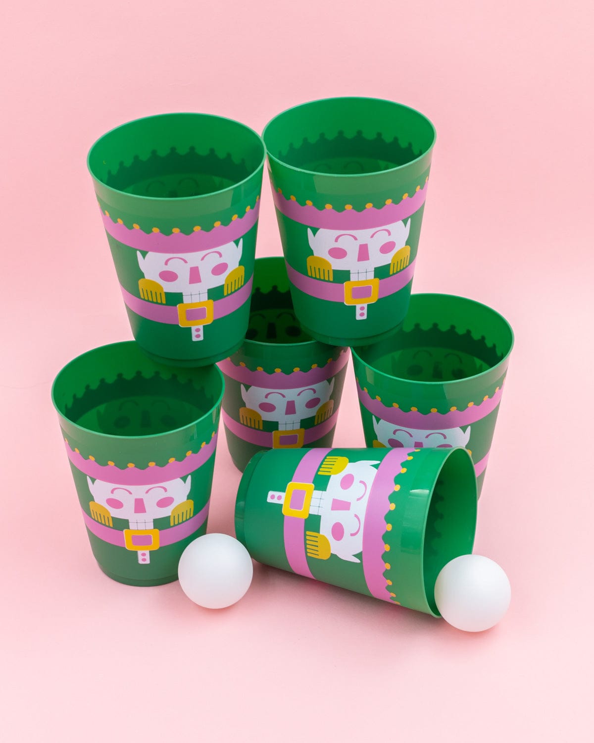 Close up of green cup design and ping pong balls shot against pink background. 