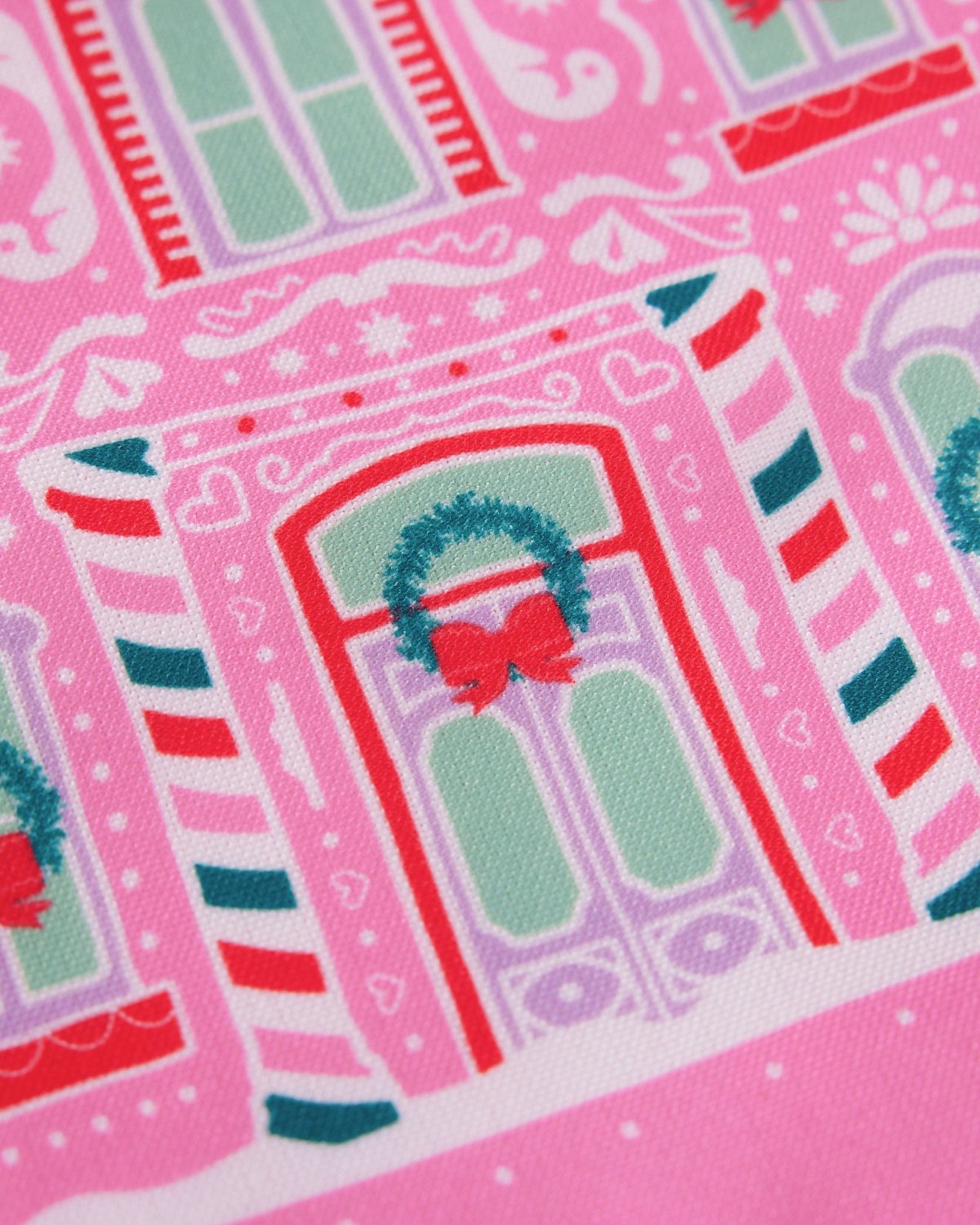 Close up of printed gingerbread house details on pink tea towel. 