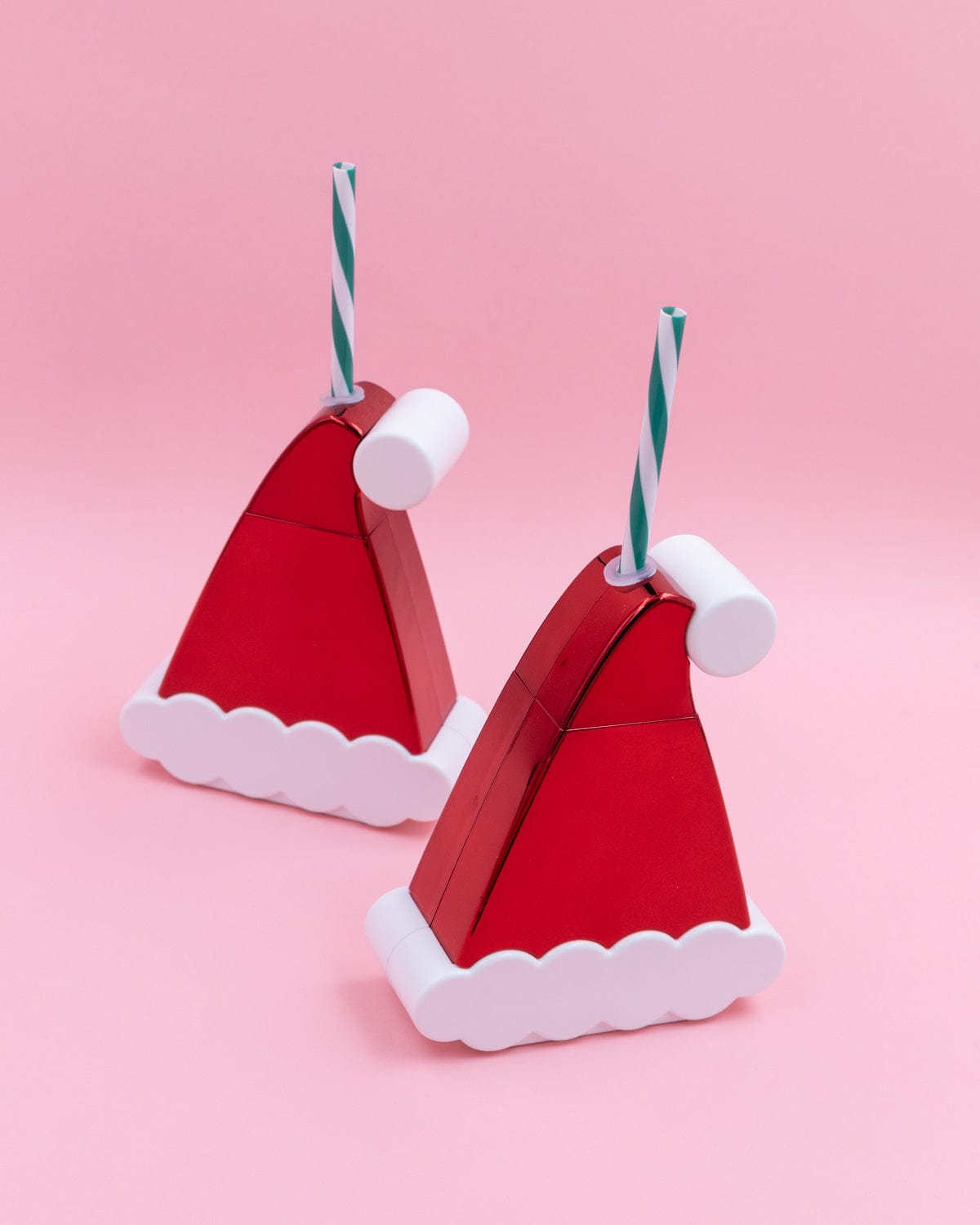Two Santa Hat Sippers shot against pink background. 