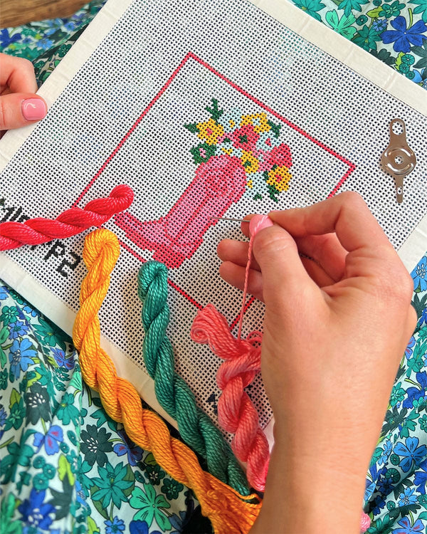 girl working on needlepoint craft in front of her floral dress