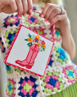 girl holding needlepoint craft in front of her colorful knitted sweater