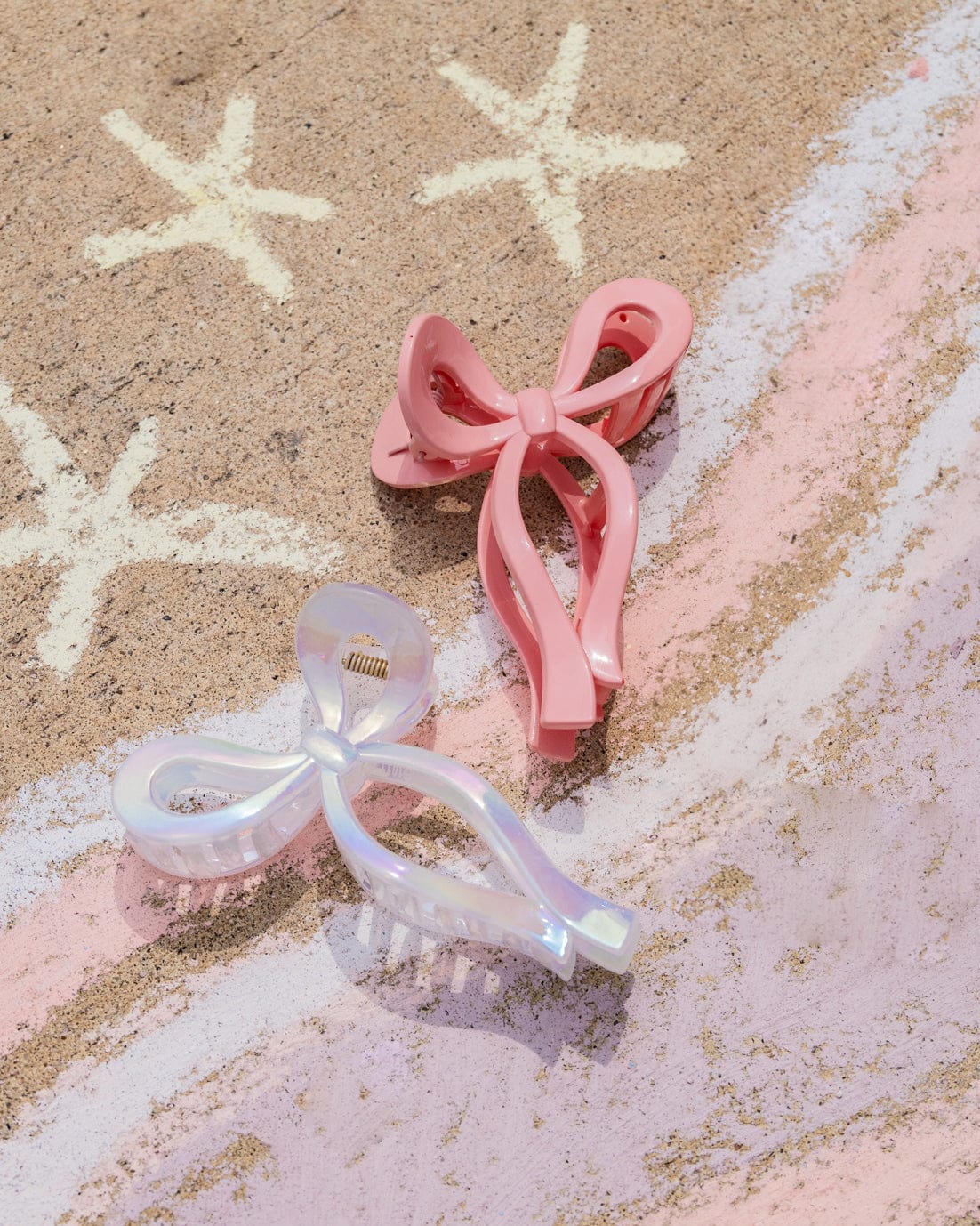 Two bow claw clips sit on top of a chalk drawing. 