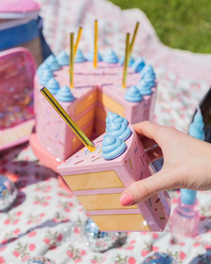 A set of 6 cake slice sippers with gold straws. Cake sipper in hand at a picnic scene