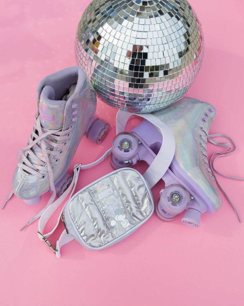 A shiny silver belt bag against pink backdrop with disco ball and roller skates. Shiny and iridescent, metallic colors.