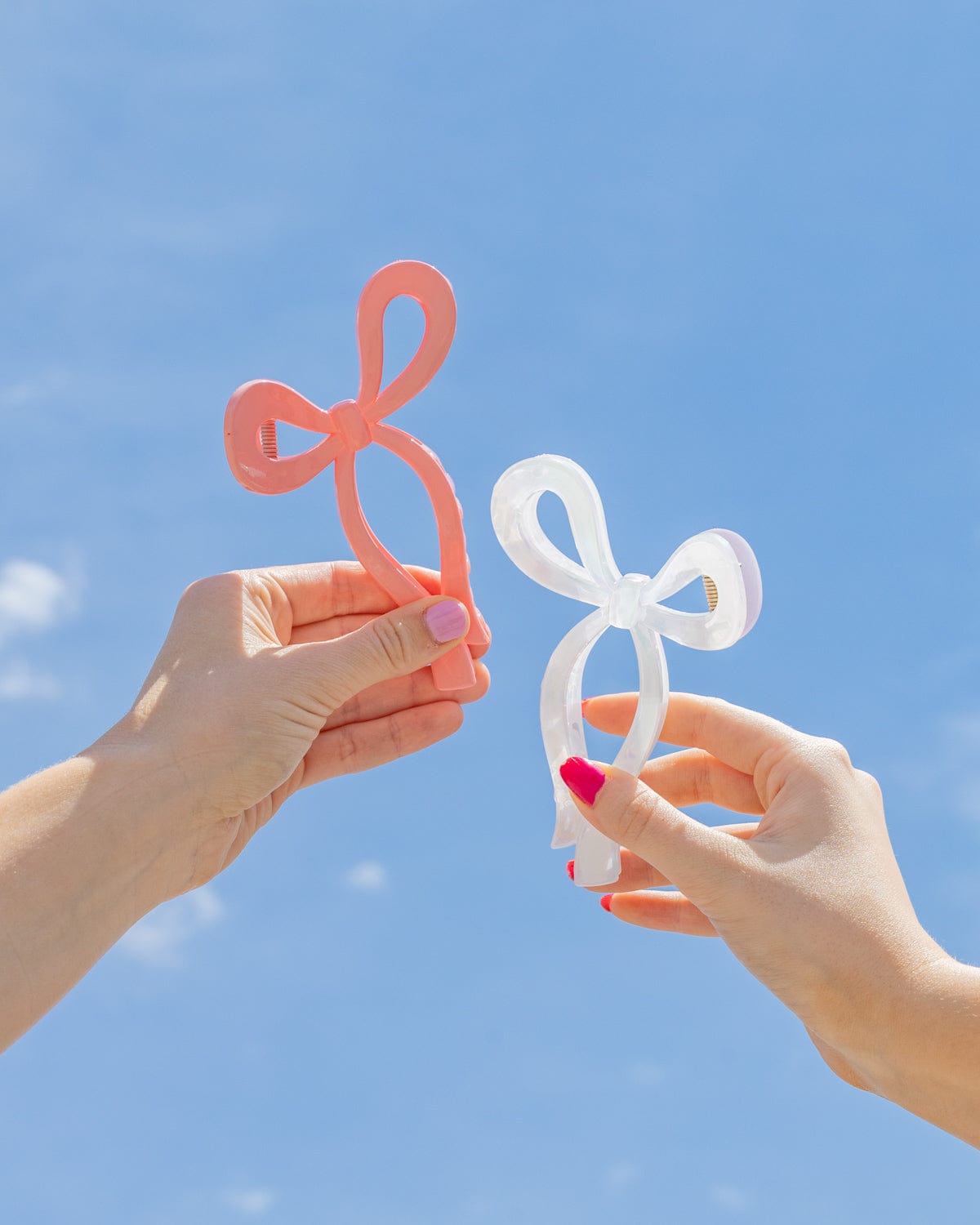 Two people hold up the bow claw clips to the sky. 