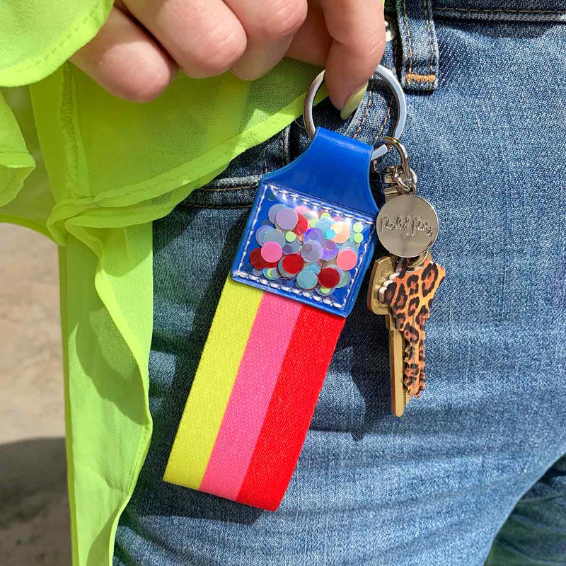 Red, pink, yellow, and blue keychain with confetti in hand.