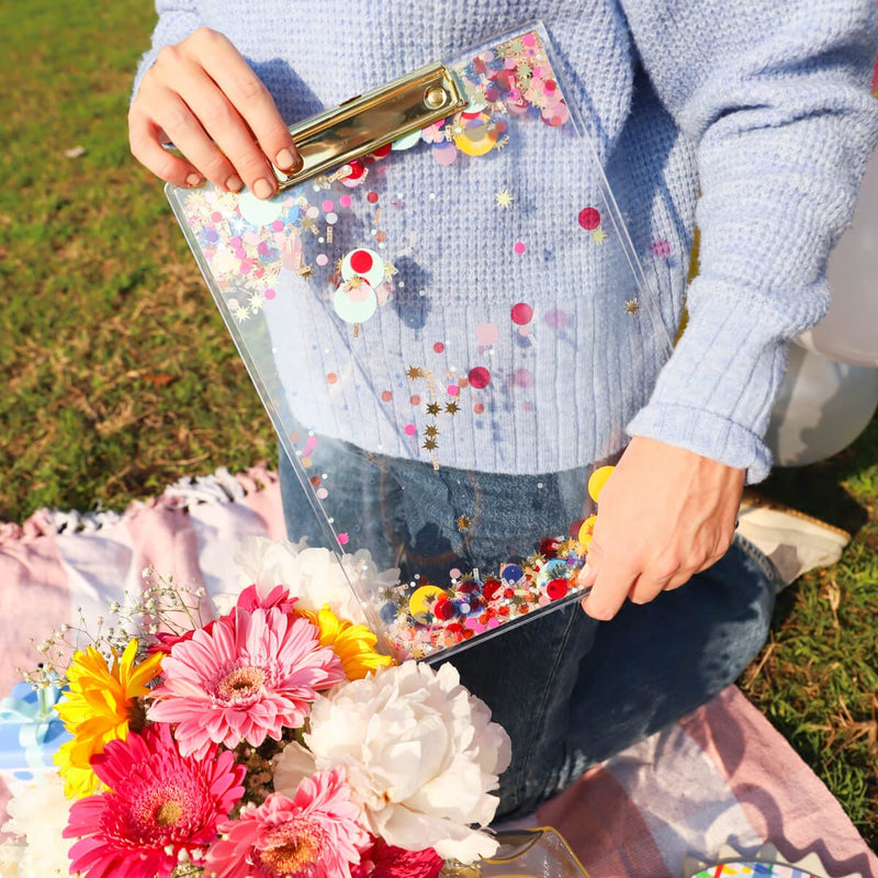 Colorful confetti clipboard cute and girly for office. Girl holding clipboard with grass and flower bouquet.