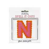 Pink and orange scalloped letter N sticker.