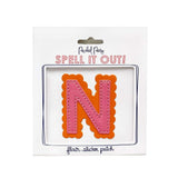 Pink and orange scalloped letter N sticker.